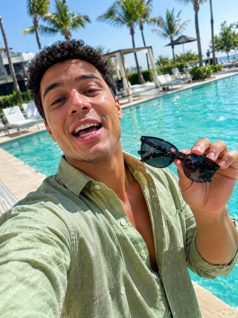 Criador de conteúdo gravando um vídeo na beira da piscina e mostrando um óculos de sol