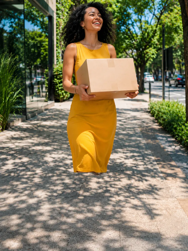 Mulher andando na rua com a encomenda que acabou de receber