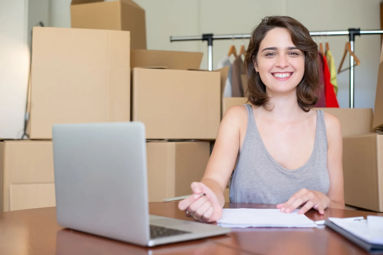 Empreendedora sorrindo no notebook entre caixas de pedido
