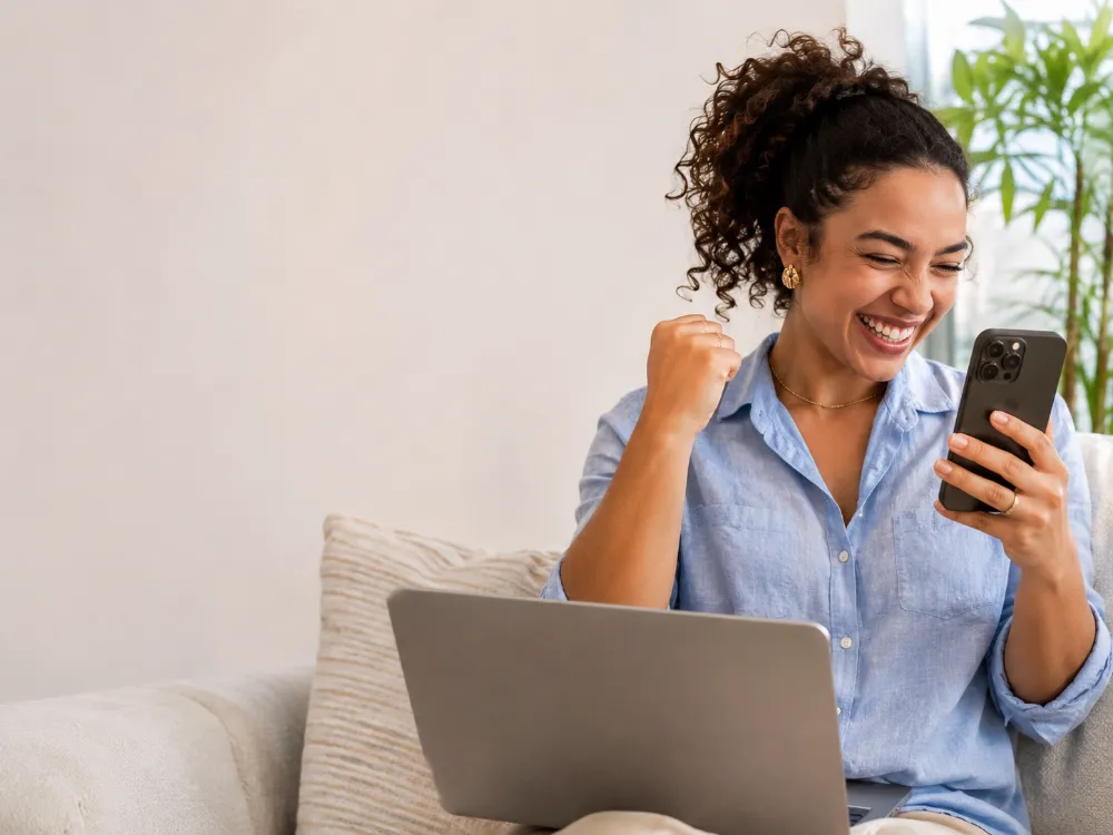 Empreendedora comemorando uma venda no celular, sem estoque em casa